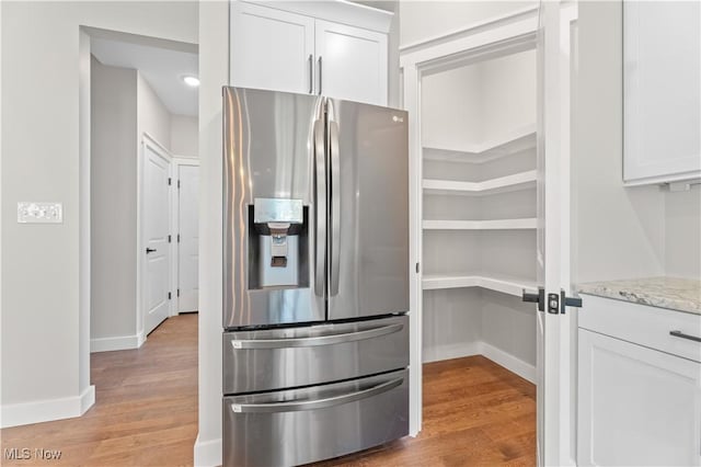 interior space with white cabinets, stainless steel refrigerator with ice dispenser, and light hardwood / wood-style floors