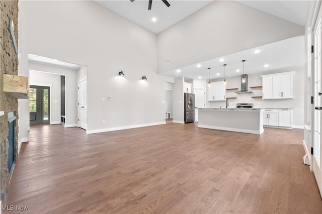 unfurnished living room with wood-type flooring, a fireplace, and high vaulted ceiling