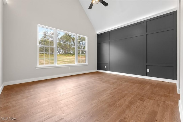 empty room with ceiling fan, high vaulted ceiling, and light hardwood / wood-style flooring