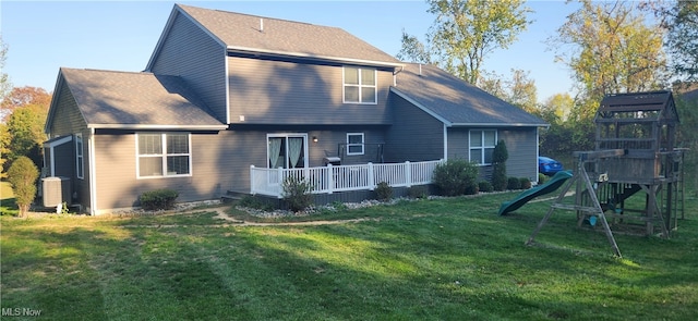 back of house featuring a playground, a deck, and a lawn