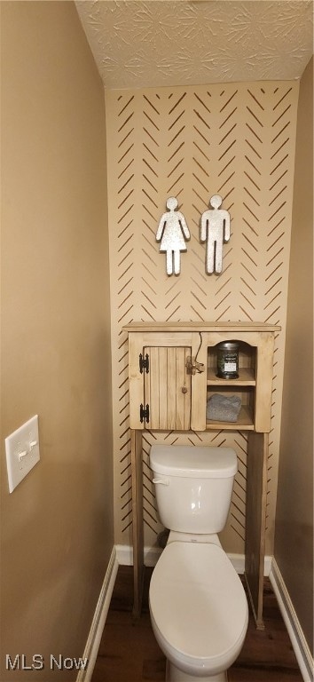 bathroom with hardwood / wood-style flooring, toilet, and a textured ceiling