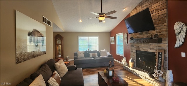 living room with wood-type flooring, ceiling fan, high vaulted ceiling, and a stone fireplace