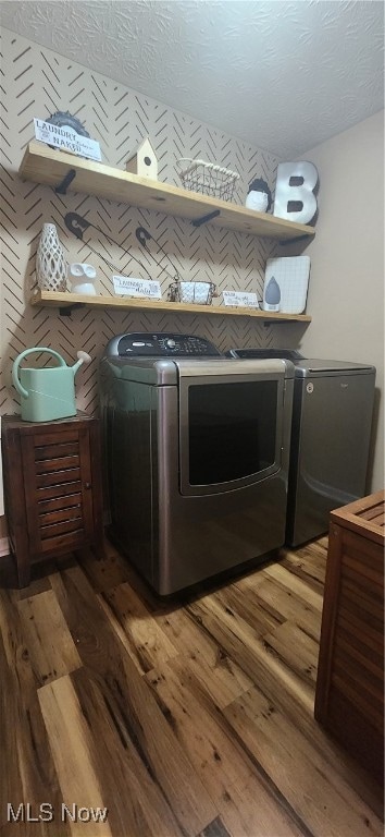 clothes washing area with washing machine and dryer, dark hardwood / wood-style flooring, and a textured ceiling