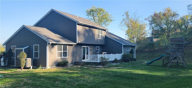 rear view of property with a playground and a lawn