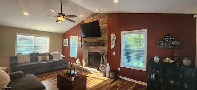 living room featuring ceiling fan, a wealth of natural light, dark wood-type flooring, and a stone fireplace