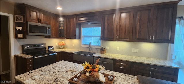 kitchen featuring light stone countertops, decorative backsplash, sink, appliances with stainless steel finishes, and dark brown cabinets