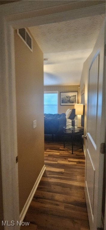 hallway featuring a textured ceiling and dark hardwood / wood-style flooring