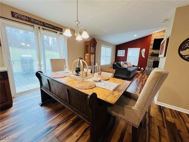 dining area featuring lofted ceiling, dark hardwood / wood-style flooring, a textured ceiling, and an inviting chandelier