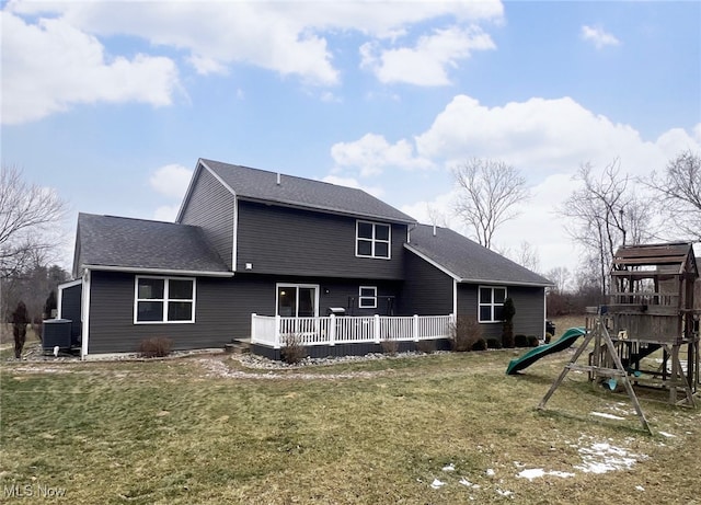 back of house with a playground, a lawn, and central air condition unit