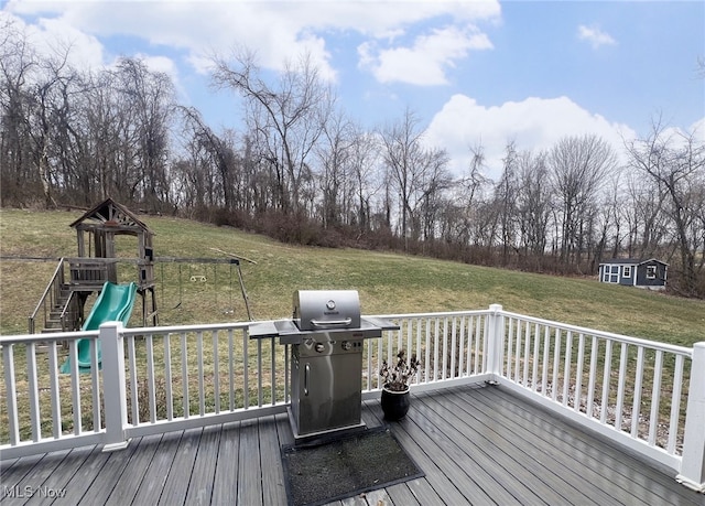 wooden deck featuring grilling area, a playground, and a lawn