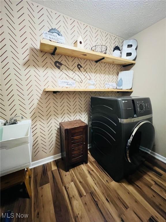 clothes washing area featuring wood-type flooring and a textured ceiling