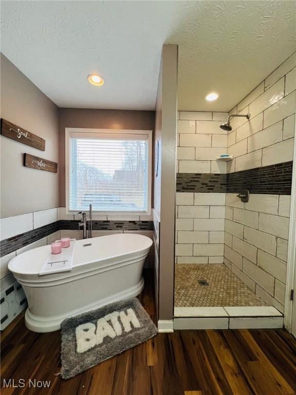 bathroom featuring hardwood / wood-style flooring, independent shower and bath, tile walls, and a textured ceiling