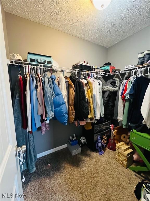 walk in closet featuring dark colored carpet