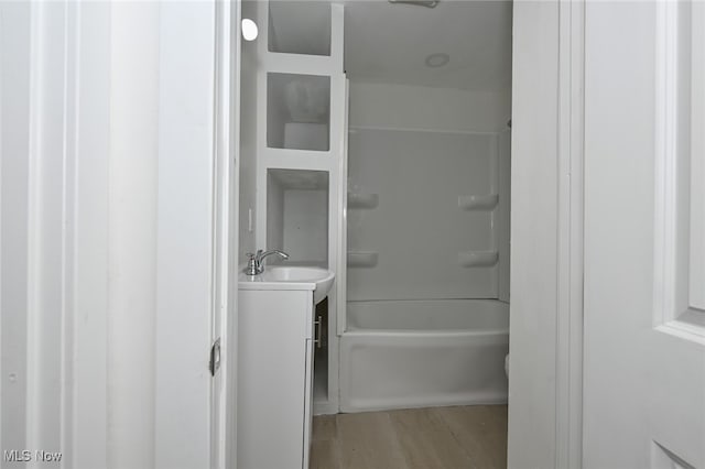 bathroom with washtub / shower combination, vanity, and hardwood / wood-style floors