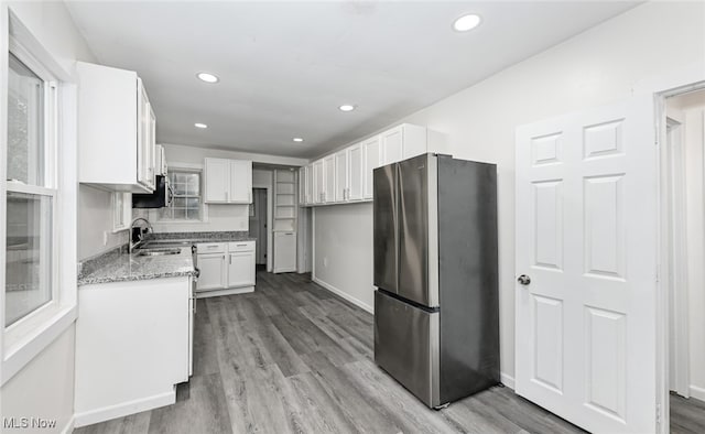 kitchen featuring light stone counters, light hardwood / wood-style floors, sink, white cabinetry, and stainless steel fridge