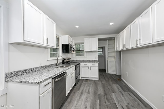 kitchen featuring wood-type flooring, sink, white cabinets, stainless steel appliances, and light stone countertops