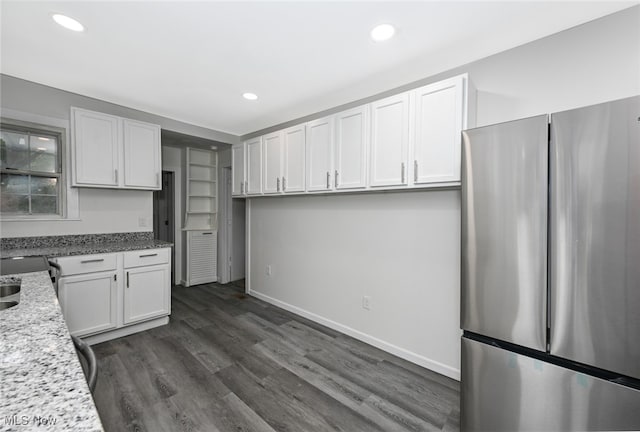 kitchen with white cabinets, stainless steel refrigerator, light stone countertops, and dark wood-type flooring