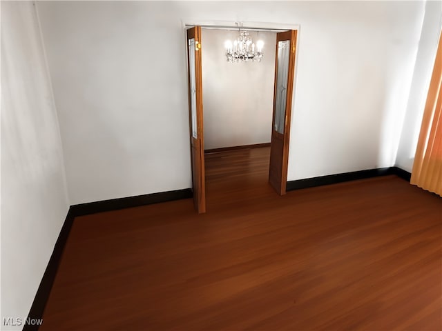 spare room featuring dark hardwood / wood-style floors and a chandelier