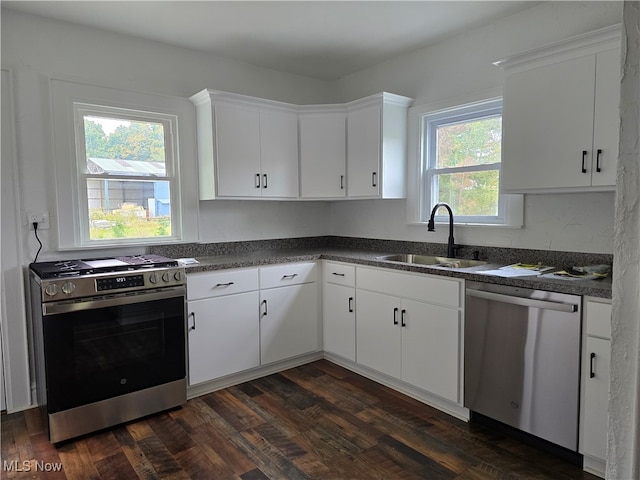 kitchen featuring a wealth of natural light, sink, white cabinetry, appliances with stainless steel finishes, and dark hardwood / wood-style flooring