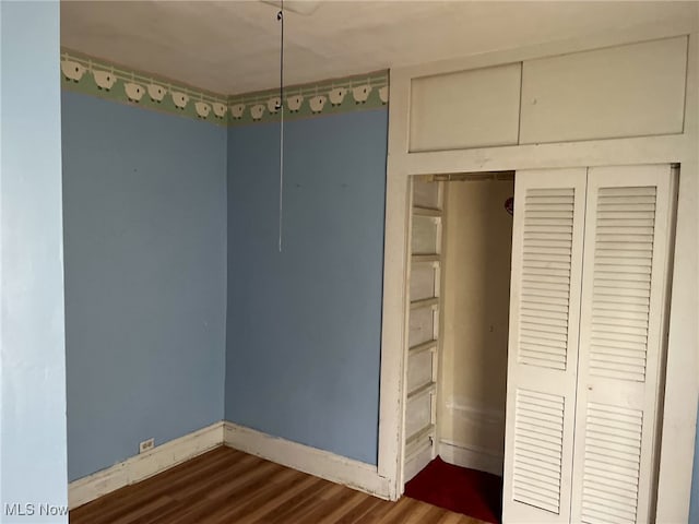 unfurnished bedroom with a closet and dark wood-type flooring