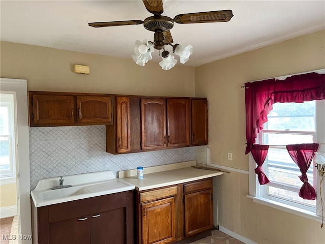 kitchen with ceiling fan, wooden walls, and sink