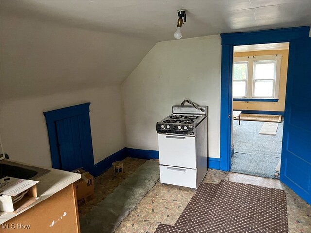 kitchen with blue cabinets, vaulted ceiling, and white gas stove