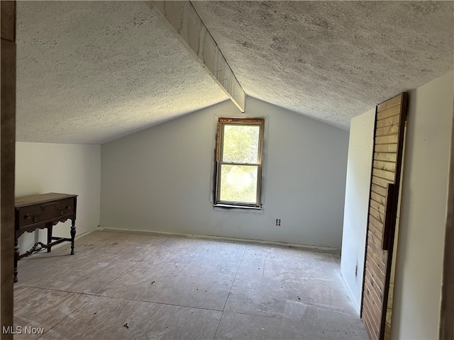 bonus room featuring lofted ceiling with beams and a textured ceiling