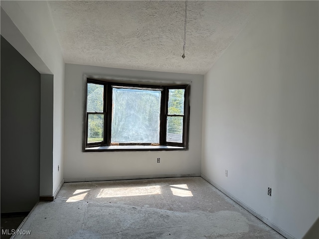 unfurnished room with vaulted ceiling and a textured ceiling