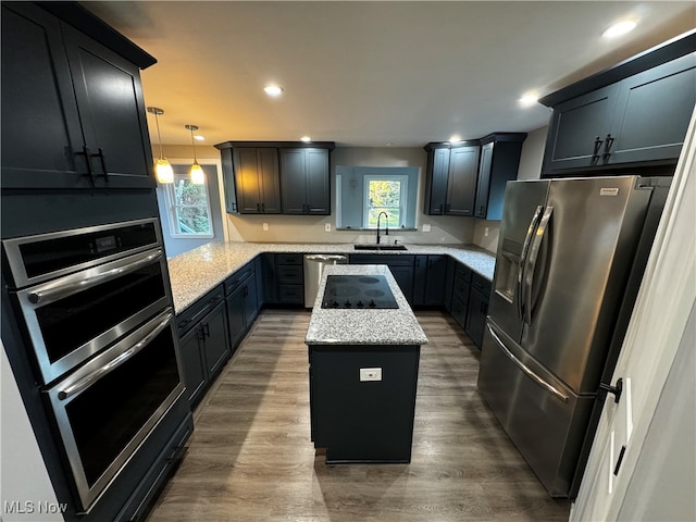 kitchen featuring decorative light fixtures, stainless steel appliances, a wealth of natural light, and a kitchen island