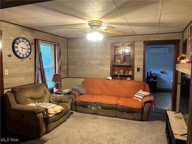 carpeted living room featuring wood walls, ceiling fan, and a wall unit AC