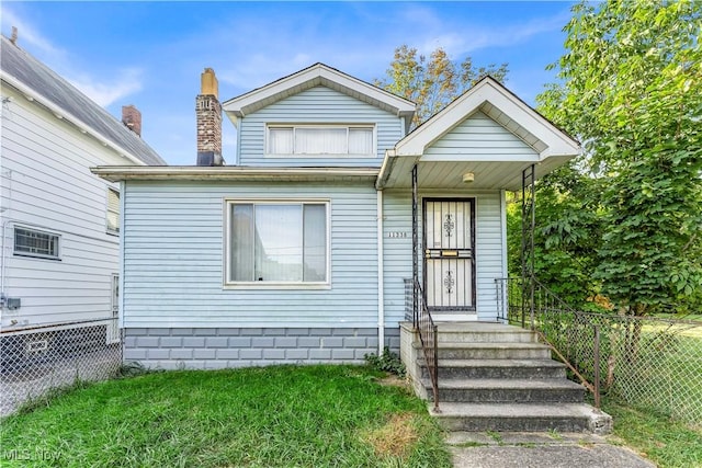 bungalow-style house featuring fence, a chimney, and a front lawn