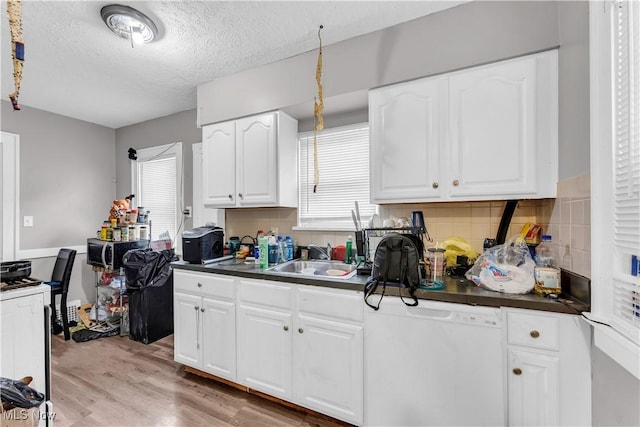 kitchen with a sink, dark countertops, tasteful backsplash, and light wood-style floors