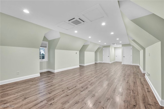 additional living space with light wood-type flooring and vaulted ceiling