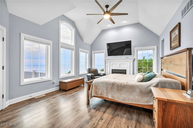 bedroom with high vaulted ceiling, multiple windows, ceiling fan, and dark hardwood / wood-style flooring