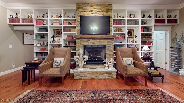 sitting room featuring crown molding, a stone fireplace, and hardwood / wood-style floors