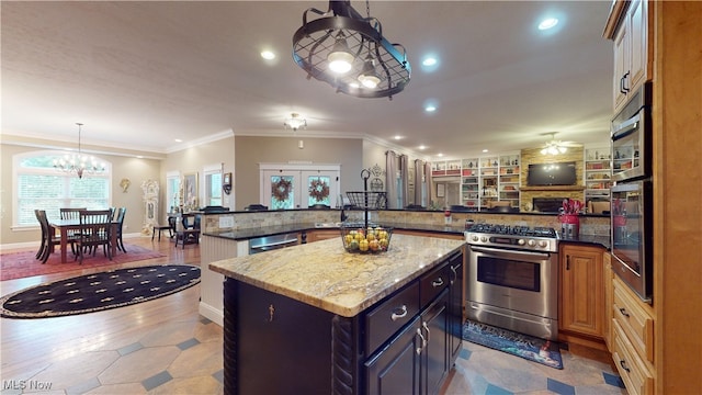 kitchen with pendant lighting, dark stone counters, ornamental molding, appliances with stainless steel finishes, and a center island