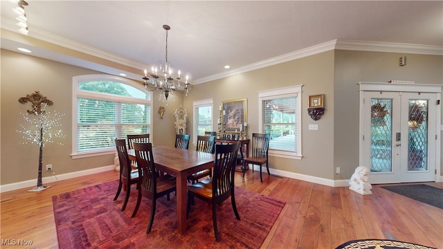 dining space with french doors, crown molding, hardwood / wood-style floors, and a chandelier