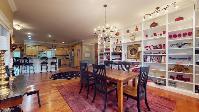 dining space featuring ornamental molding, light hardwood / wood-style flooring, and a chandelier