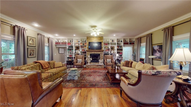 living room featuring ornamental molding, built in shelves, light hardwood / wood-style flooring, and ceiling fan