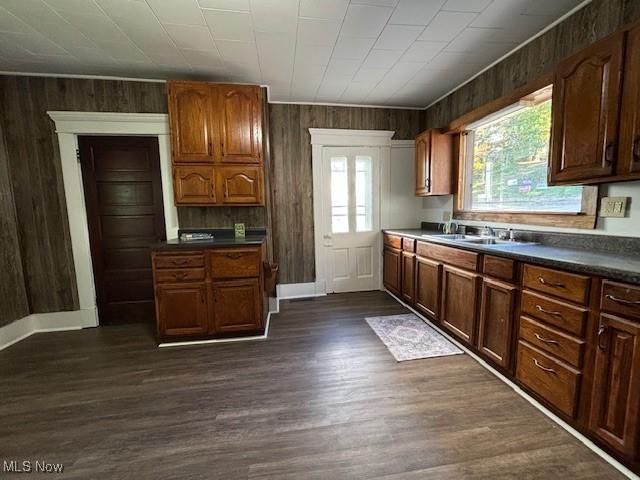 805 Quarry St, Marietta, OH 45750 - kitchen with a sink, dark countertops, dark wood-type flooring, wood walls, and baseboards