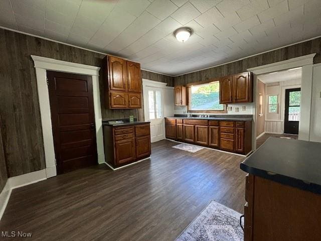 805 Quarry St, Marietta, OH 45750 - kitchen featuring wooden walls, healthy amount of natural light, dark wood-style flooring, dark countertops, and brown cabinets
