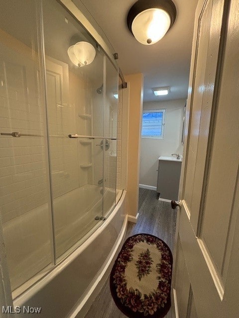 bathroom with vanity, hardwood / wood-style floors, and enclosed tub / shower combo