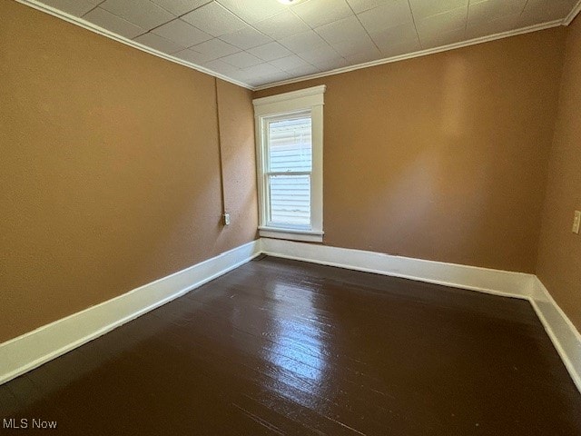 spare room featuring dark hardwood / wood-style floors and crown molding