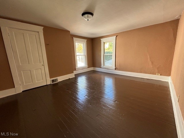 empty room with dark hardwood / wood-style flooring