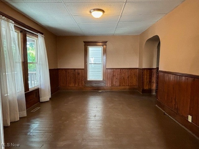 spare room featuring a drop ceiling, wood walls, and dark hardwood / wood-style floors