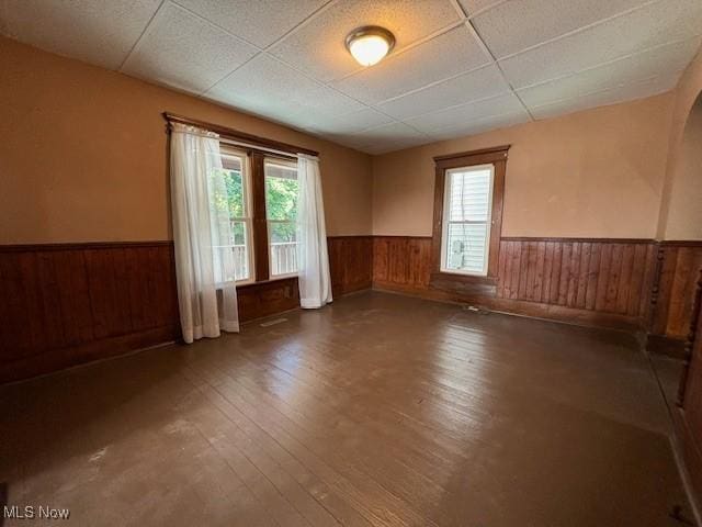 805 Quarry St, Marietta, OH 45750 - empty room with wainscoting, healthy amount of natural light, hardwood / wood-style floors, wood walls, and a drop ceiling