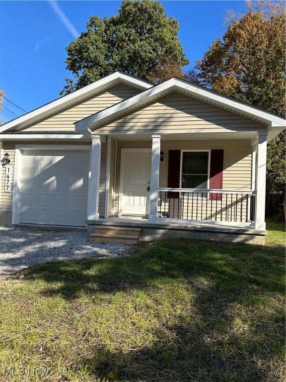 view of front of property featuring a porch, a front lawn, and a garage