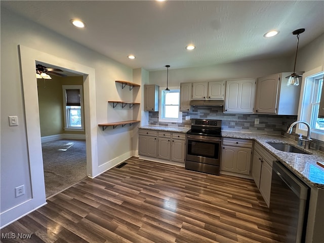 kitchen with light stone counters, sink, hanging light fixtures, decorative backsplash, and appliances with stainless steel finishes