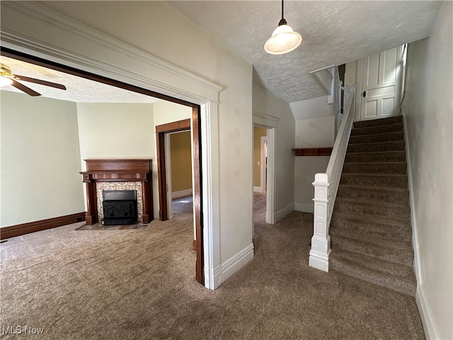 stairway featuring a textured ceiling, ceiling fan, and carpet floors