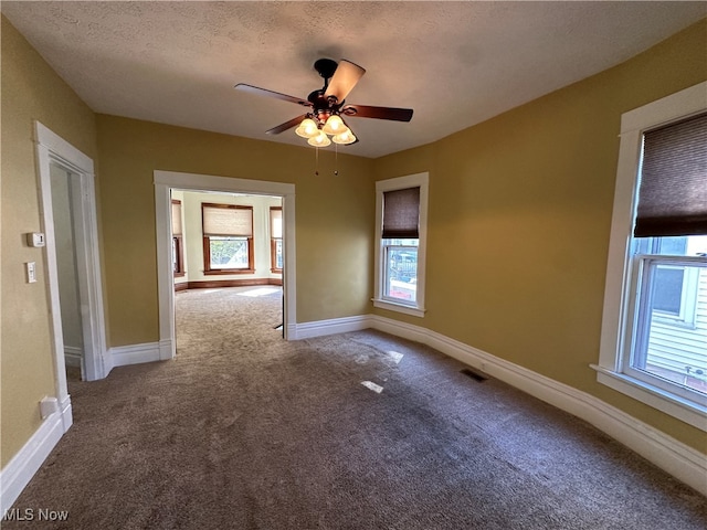 carpeted spare room with ceiling fan, a textured ceiling, and a healthy amount of sunlight